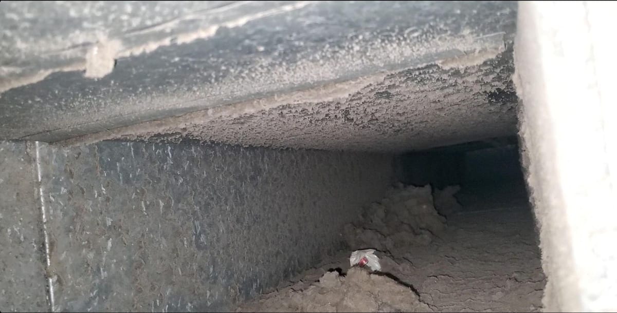 Inside an air duct, with heavy dust along the seam